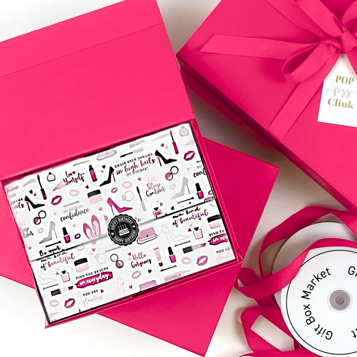 A bright pink gift box set with a ribbon and a printed insert card featuring cosmetics and fashion illustrations. The insert card includes a circular logo that reads 'POP for Clink'.